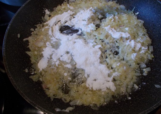 Zwiebel und Knoblauch in Pfanne anschwitzen, mehlieren. Normalerweise werden hier die Speckwürfel gleich mitgebraten.  TIPP: Falls Vegetarier/innen mitessen, den Speck separat anbraten und extra anbieten 