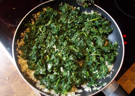 Den Spinat zu Zwiebeln und Knoblauch in die Pfanne geben, kurz mitdünsten lassen..