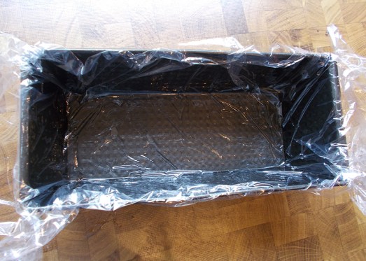 Kastenform etwas einölen und  mit Klarsichtfolie auslegen (durch das Öl hält die Folie besser).