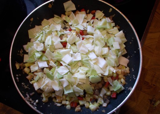 Dann das geschnittene Kraut beigeben und gut vermischen. Das Kraut lässt Wasser, also ist keine zusätzliche Flüssigkeit nötig. Deckel drauf, und bei mittlerer Hitze dünsten lassen, ab und zu umrühren, bis das Kraut weich ist. Das geht relativ flott.