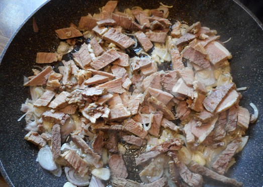 Zwiebel und Knoblauch anrösten, Rindfleisch dazugeben, gemeinsam durchrösten lassen.